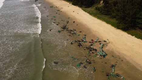 aerial view of tropical sandy beach in vietnam with plastic fishing net washed out after thyphoon storm during monsoon season, ocean pollution climate change concept