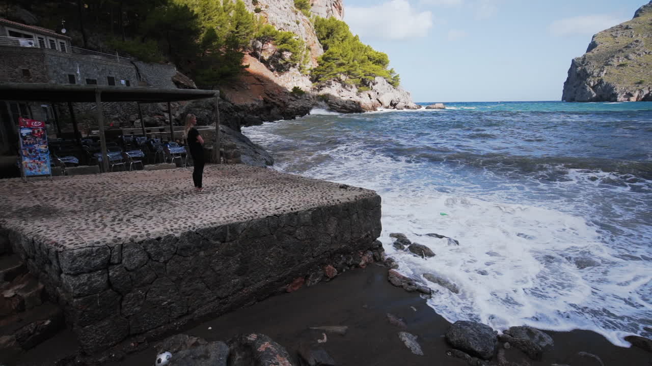 chica mira las olas en el puerto de sa calobra, mallorca