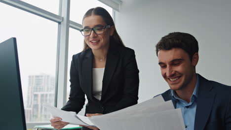 Closeup-smiling-managers-working-analysing-documents-computer-data-in-office.