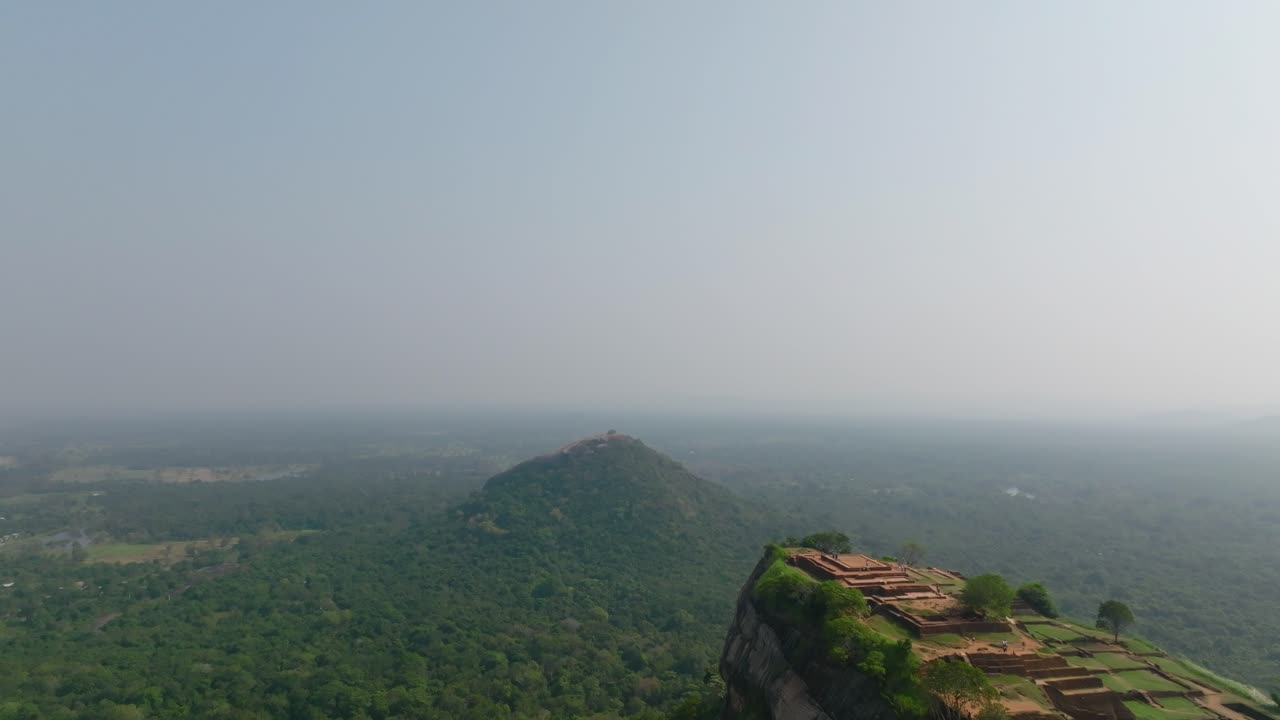 Dronebilde av Sigiriya-toppens ruiner og hager på det massive fjellplatået over den endeløse skogen på Sri Lanka