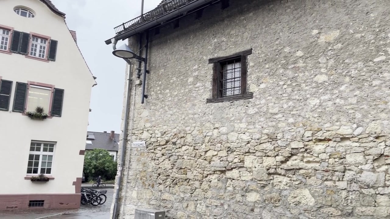 Una carrellata fluida inizia dal complesso storico del municipio e prosegue lungo un vecchio muro di pietra con architettura tradizionale in legno a Binzen, Germania