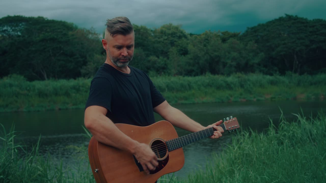 Man Playing Acoustic Guitar by a River