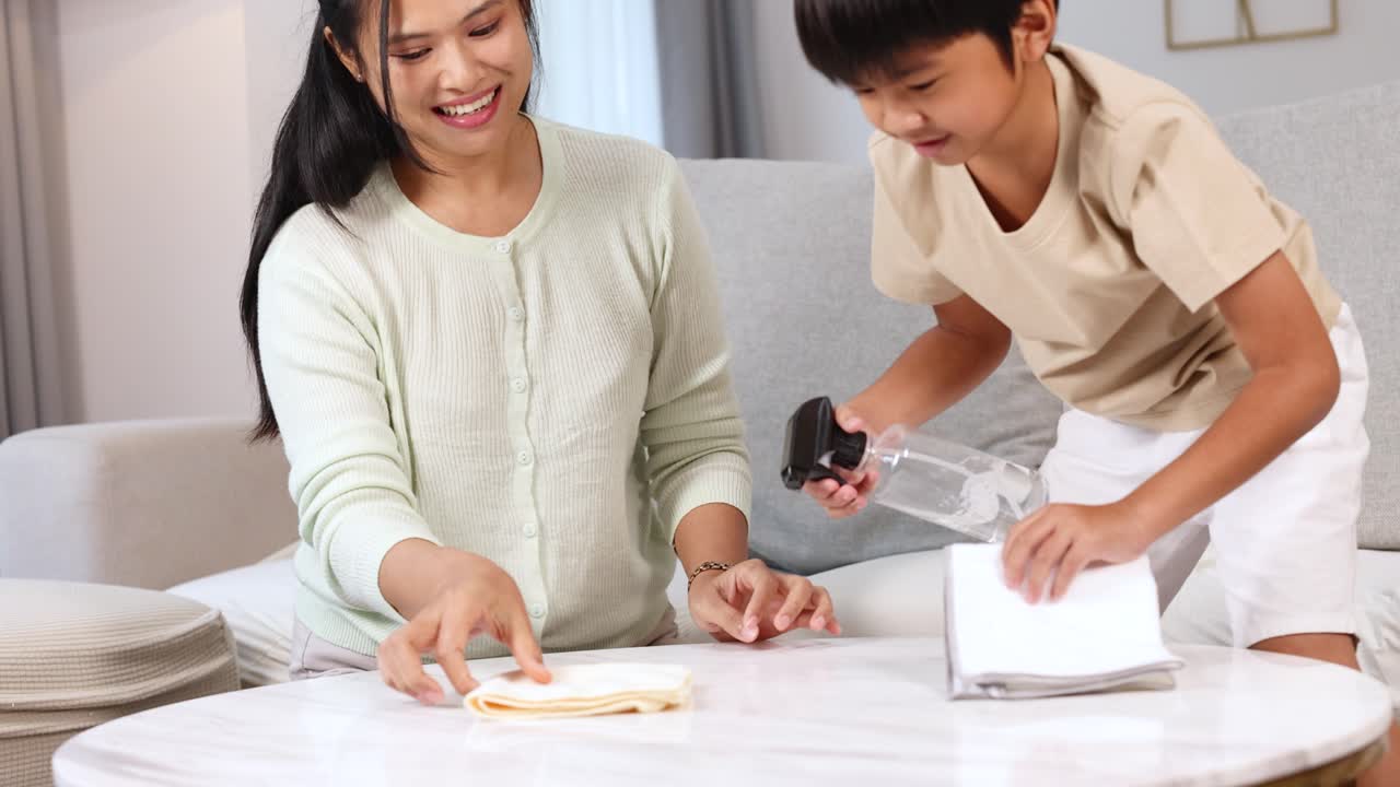 Mother and son clean table together in bright, cozy living room, fostering teamwork and bonding