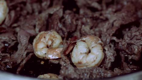 camarones chisporroteantes y bistec cocinando en la estufa en una sartén cena