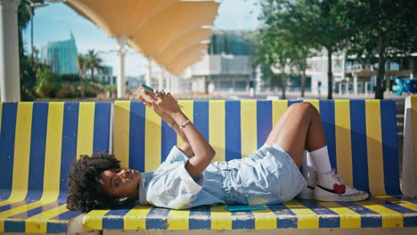 college girl holding textbook lying on bench street. teenager posing with book