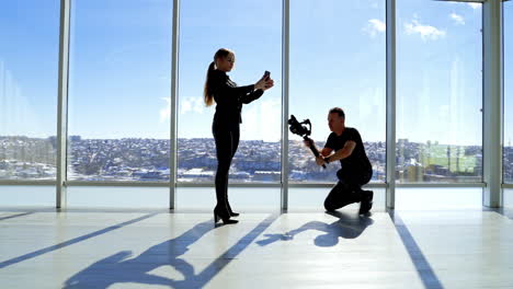 beautiful woman posing to her phone. professional photographer taking photos of a young woman doing selfie on her mobile phone on windows background.