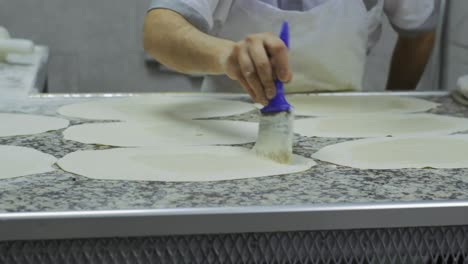 el chef frota aceite sobre la masa finamente enrollada con un cepillo