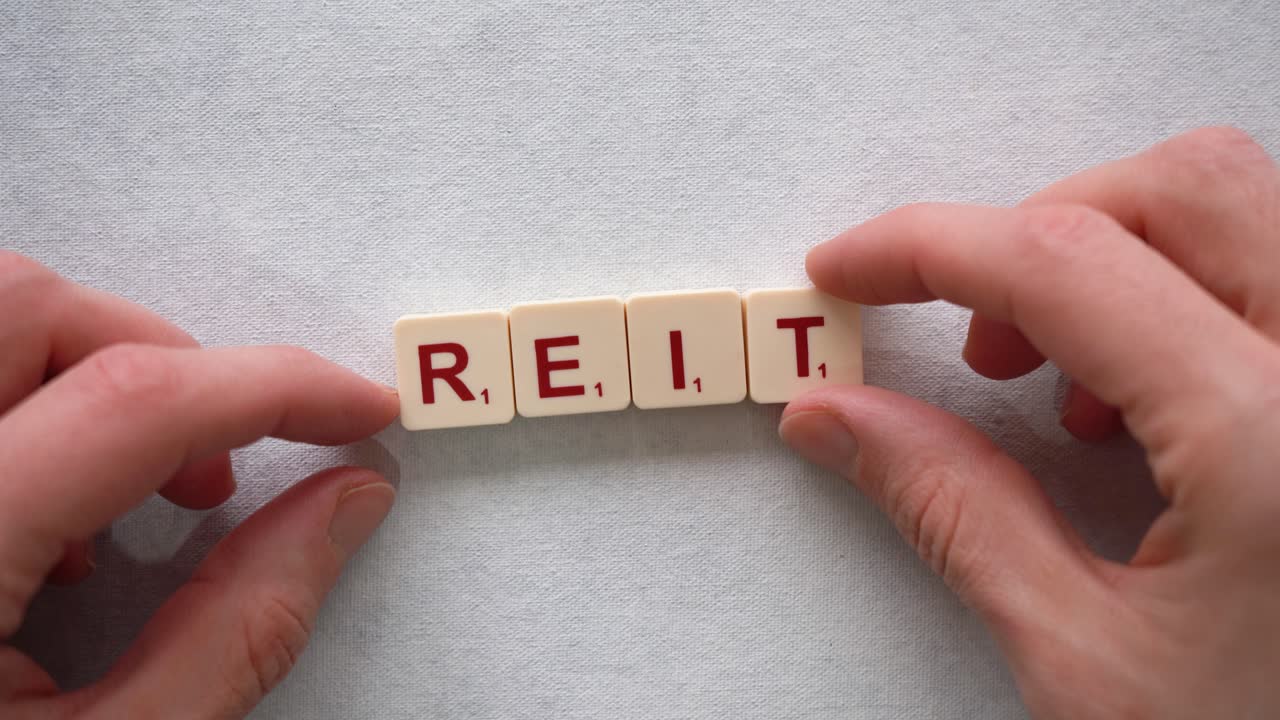 Human hands creating the word &amp;quot;REIT&amp;quot; with red letters