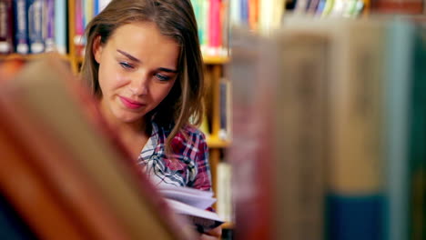 estudiante feliz leyendo un libro de pie en la biblioteca