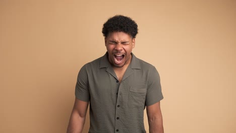 frustrated young man screaming in beige studio