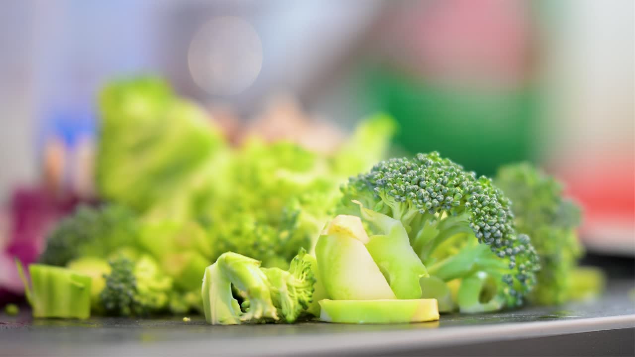 Freshly chopped broccoli is in sharp focus, ready for a healthy meal. This macro shot of ingredients on a cutting board is perfect for themes of clean eating, vegetarianism, and meal prep