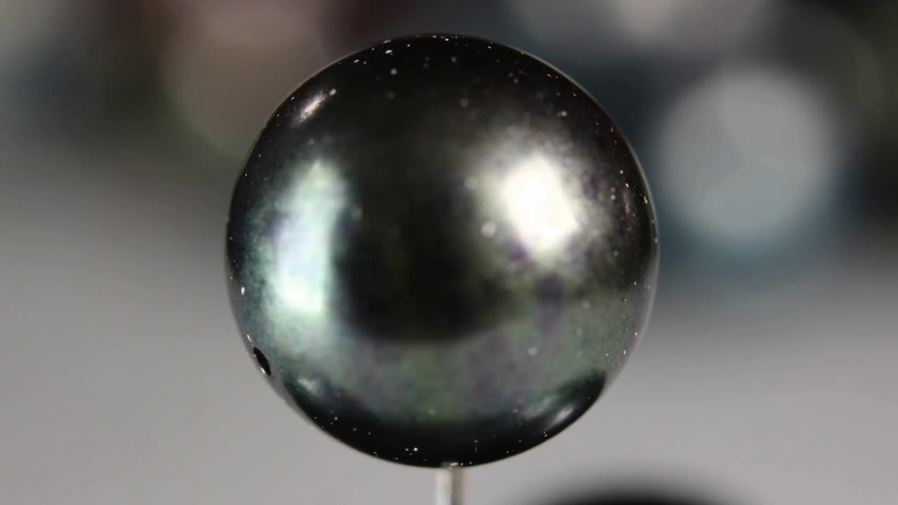 ピント調整中のカメラが研究室の細い直立ピン上の暗い金属ビーズの質感を明らかにし、ボケ効果。