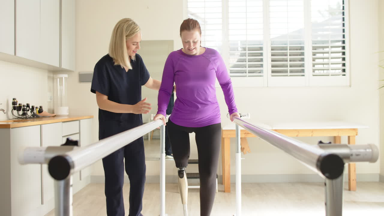 Woman in prosthetic leg walking with therapist on parallel bars in clinic