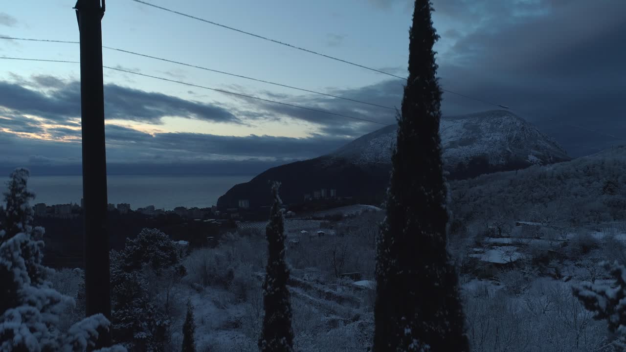 vista de la puesta de sol de la montaña nevada con la ciudad y el mar