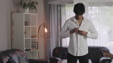 joven y elegante hombre asiático vistiéndose para la noche de graduación en la sala de estar