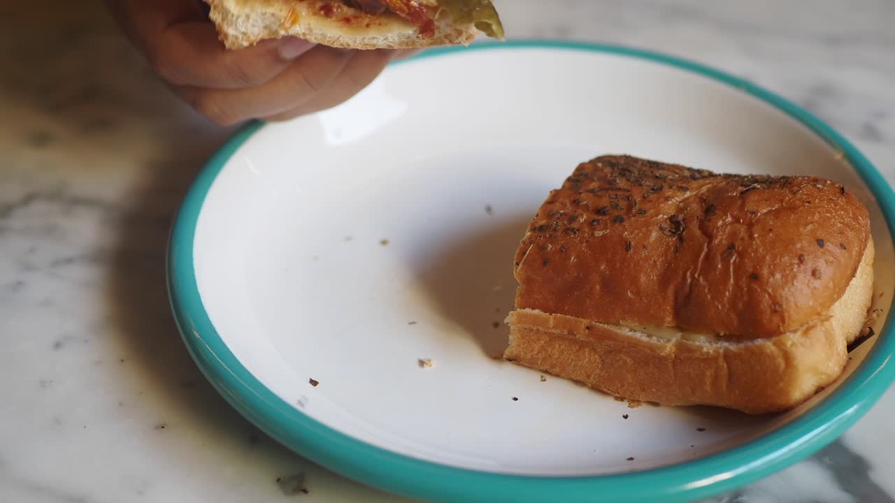 白い皿からサンドイッチを拾う手のクローズアップ