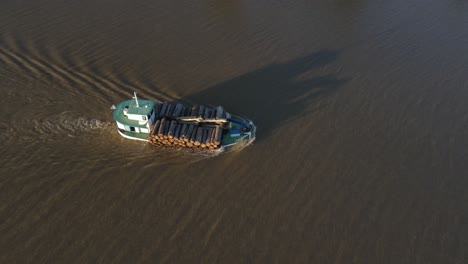 aerial orbiting shot of industrial cargo ship loaded with wood cruising on amazon river