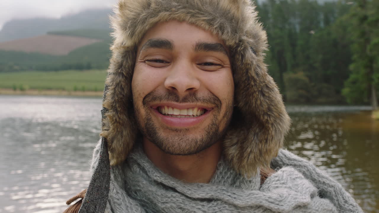 retrato atractivo joven sonriendo feliz haciendo muecas con sombrero de piel al aire libre en la naturaleza junto al lago