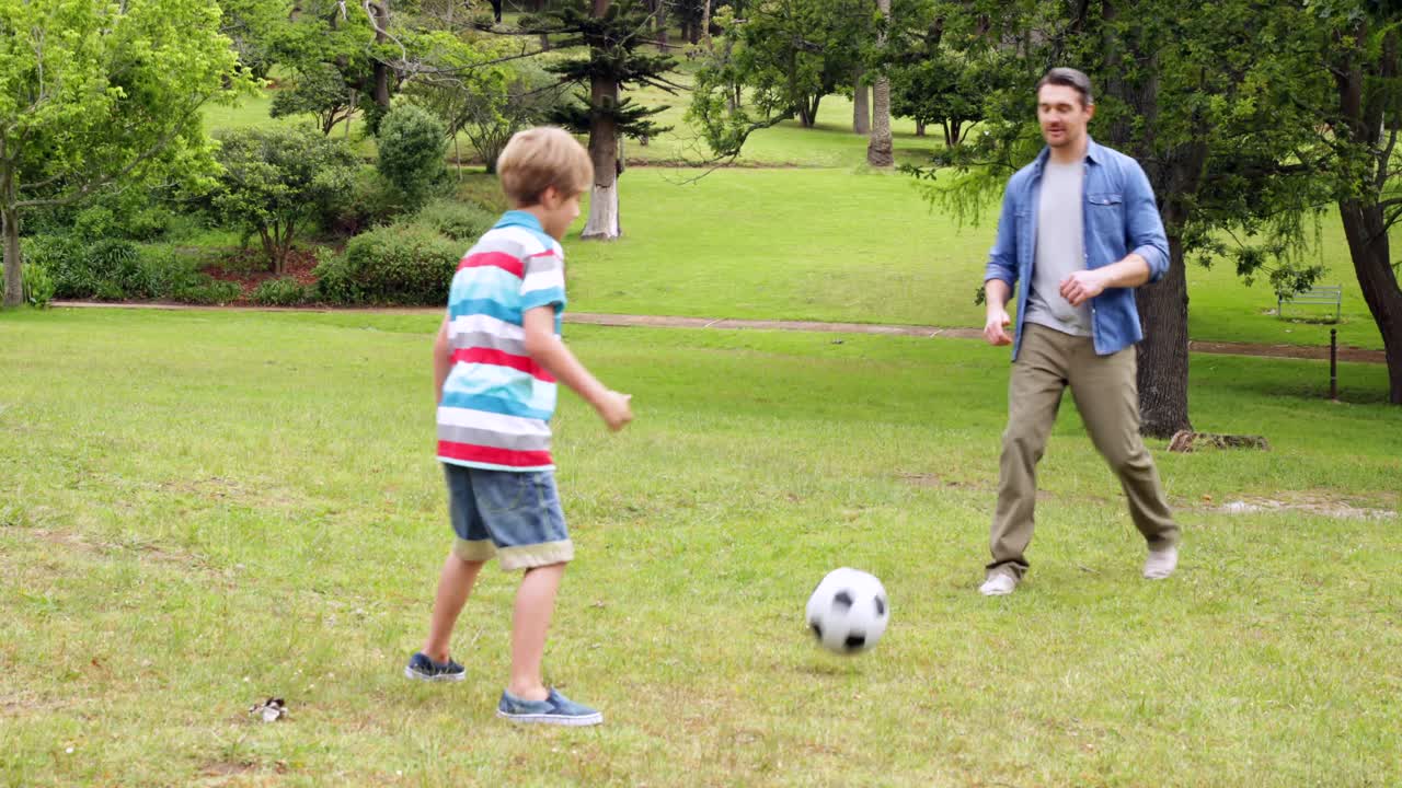 padre e hijo pateando una pelota de fútbol adelante y atrás