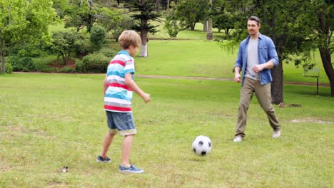 Padre-E-Hijo-Pateando-Una-Pelota-De-Fútbol-De-Un-Lado-A-Otro