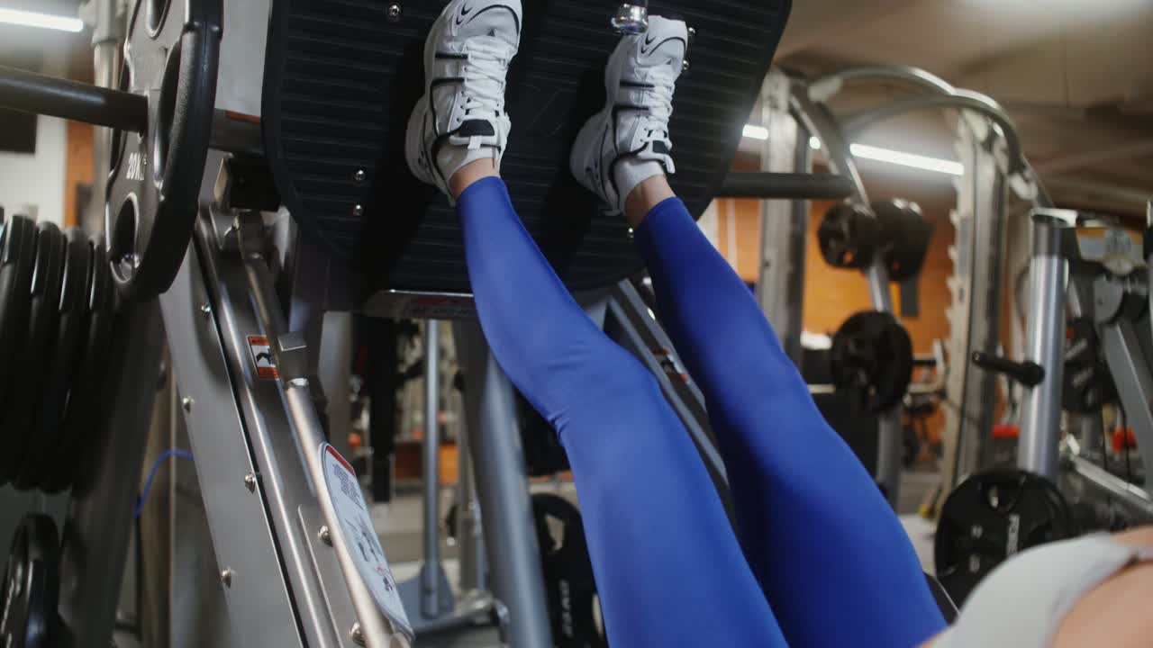 Woman working out on a leg press machine in a gym