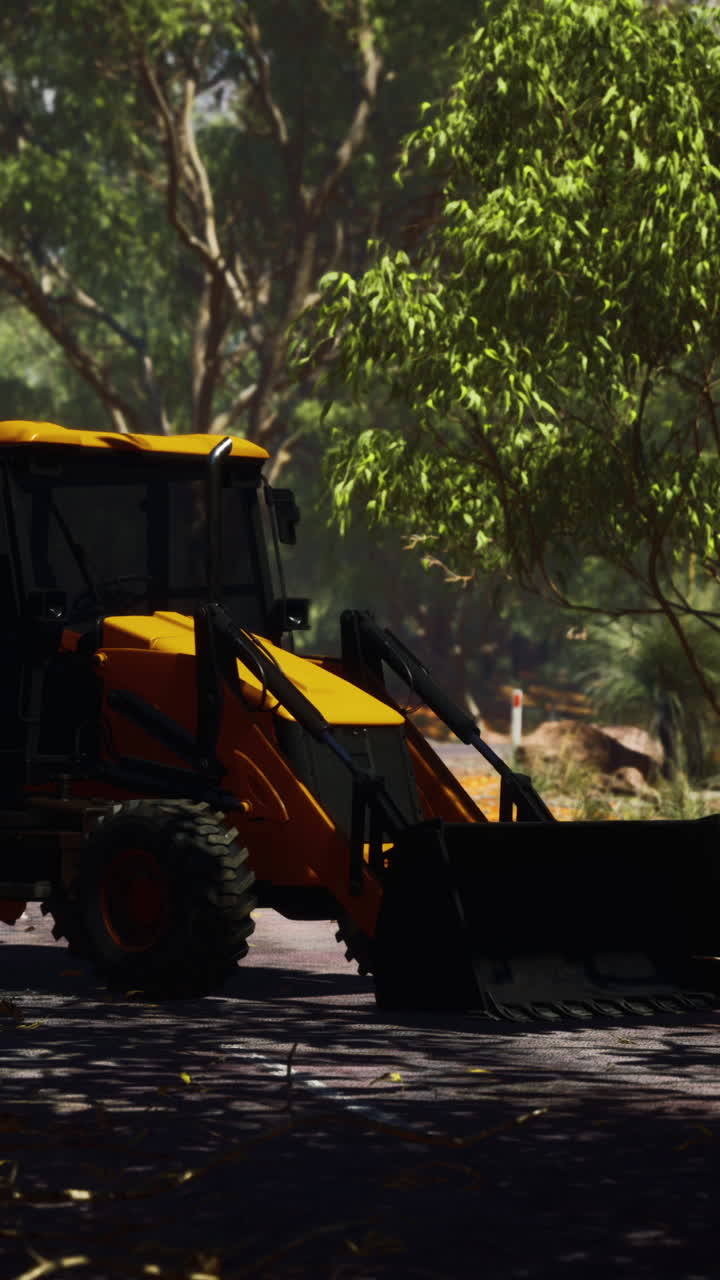 retroexcavadora amarilla en un camino cerca de los árboles