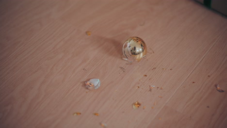 Broken-golden-bauble-on-hardwood-floor-during-Christmas