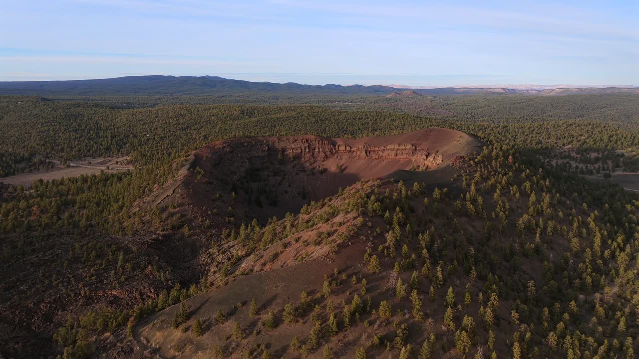 Un drone si allontana da un cratere vulcanico per rivelare una vasta foresta incontaminata. Questo volo a ritroso in 4K evidenzia la robusta scala geologica di una caldera remota e non specifica di una località.