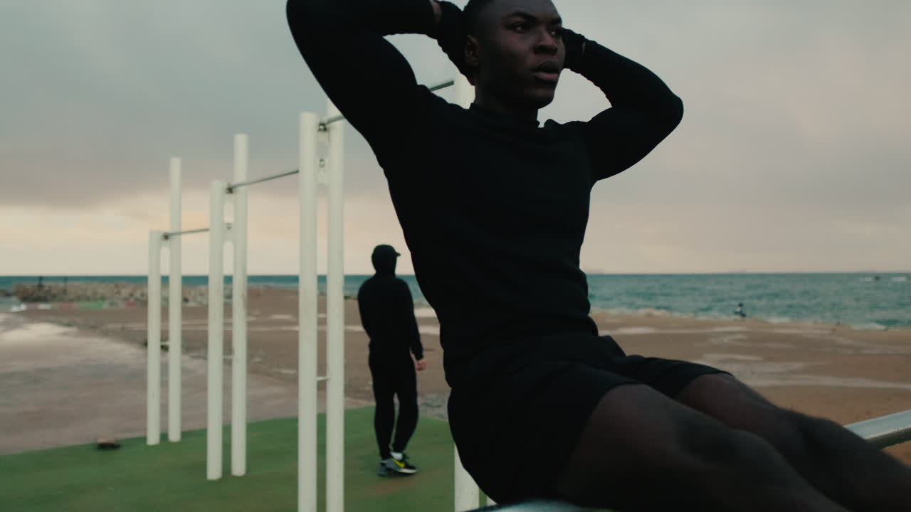 Young Black Man Doing Sit-Ups at an Outdoor Gym by the Sea
