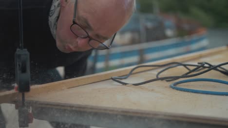 elderly carpenter blows away sawdust