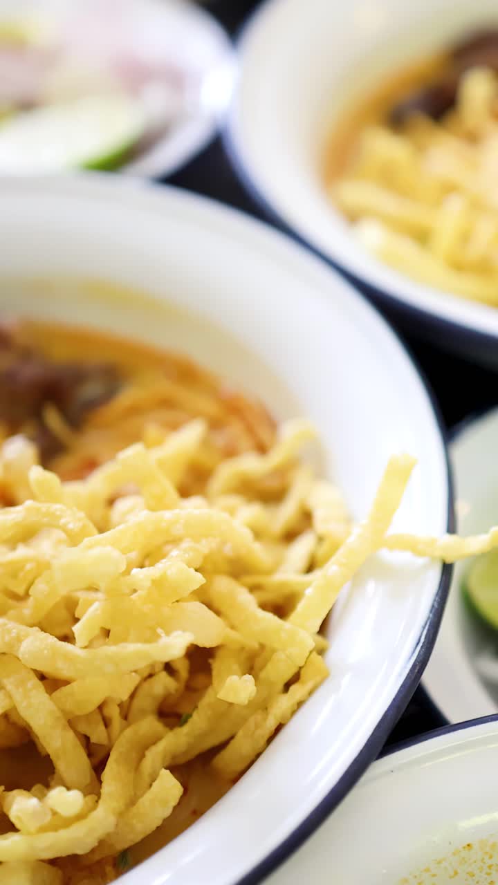 Close-up shots of beef curry noodles and fresh garnishes in a brightly lit Thai restaurant, with smooth camera movement highlighting textures and vibrant colors
