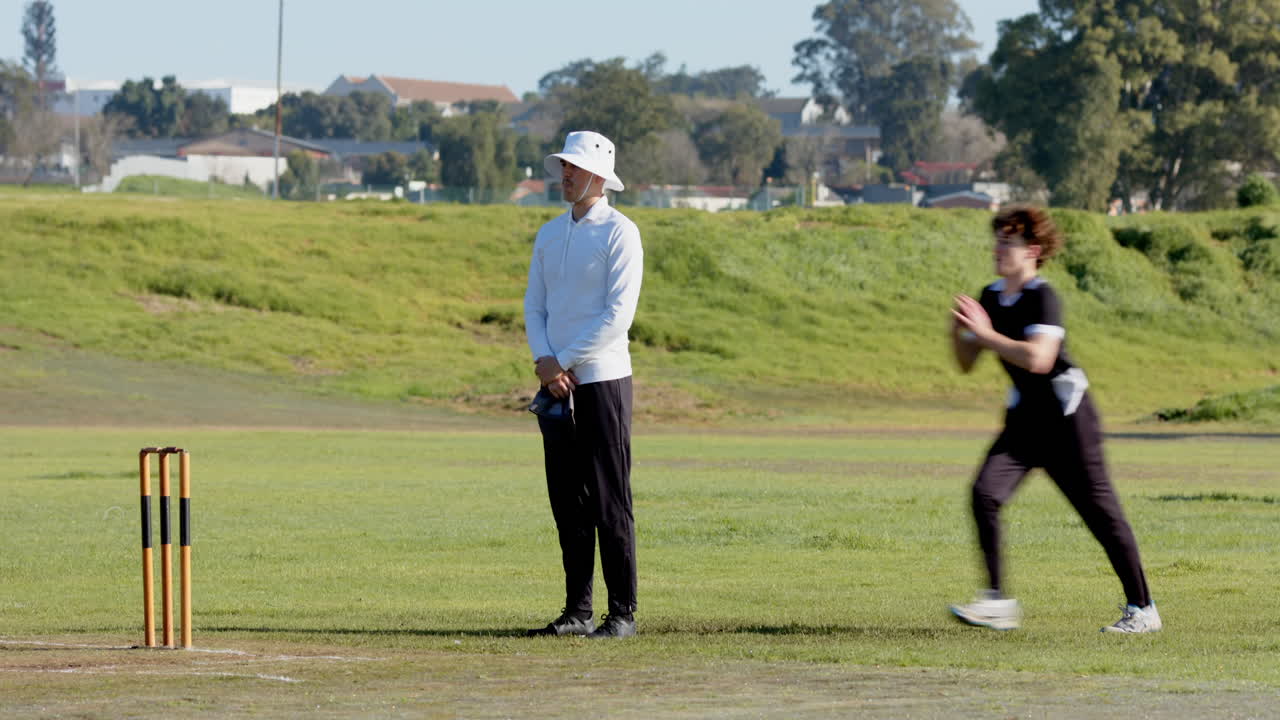 Bowler delivering fast ball on cricket field, batsman ready to play