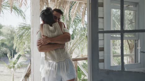 happy diverse couple embracing on sunny beach house porch, in slow motion