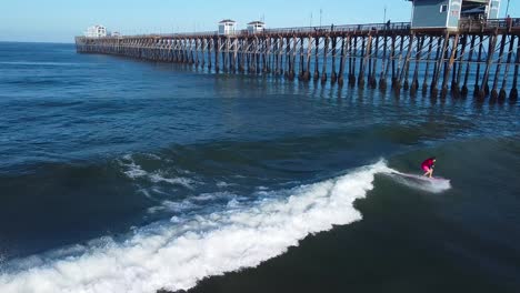 surfer on a pink longboard surfing at oceanside