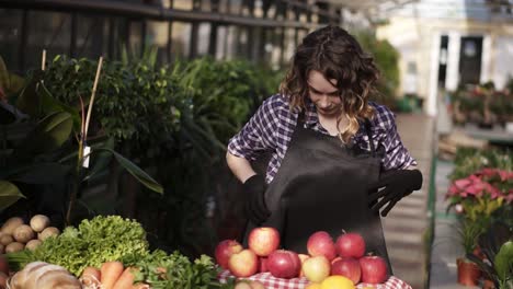 Slow-motion-footage-of-cheerful-independent-millennial-girl,-feel-confident-and-successful-in-retail,-putting-black-apron-and-ready-for-work-in-bright-indoors-greenhouse.-Grocery-shop-inside-the-greenhouse