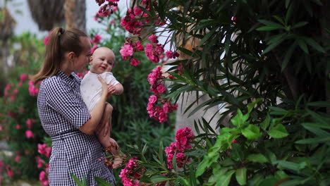 in the midst of palm trees and vibrant flowers at the resort, a mother engages in playful hugs and kisses with her child. a heartwarming portrayal of a joyful family