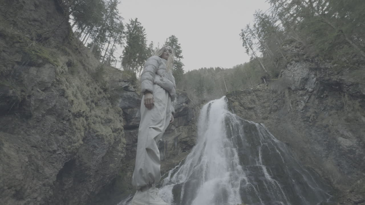 Woman standing near a waterfall in a forest