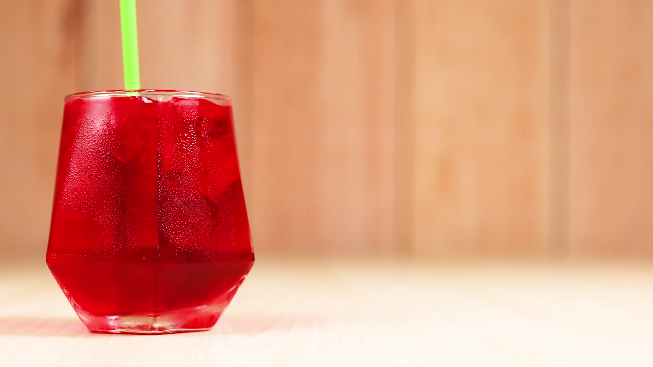 Cannuccia verde che mescola una bevanda rossa in un bicchiere