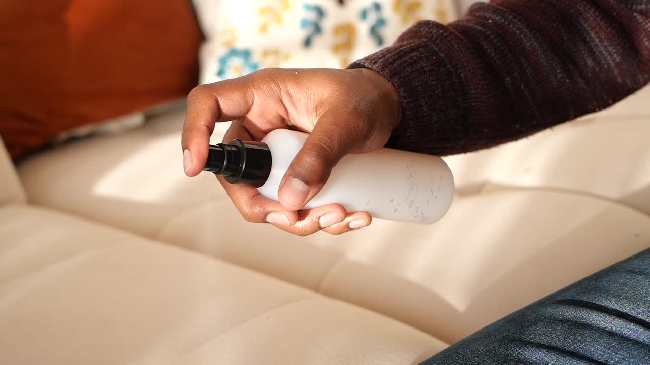 Person spraying something on a couch