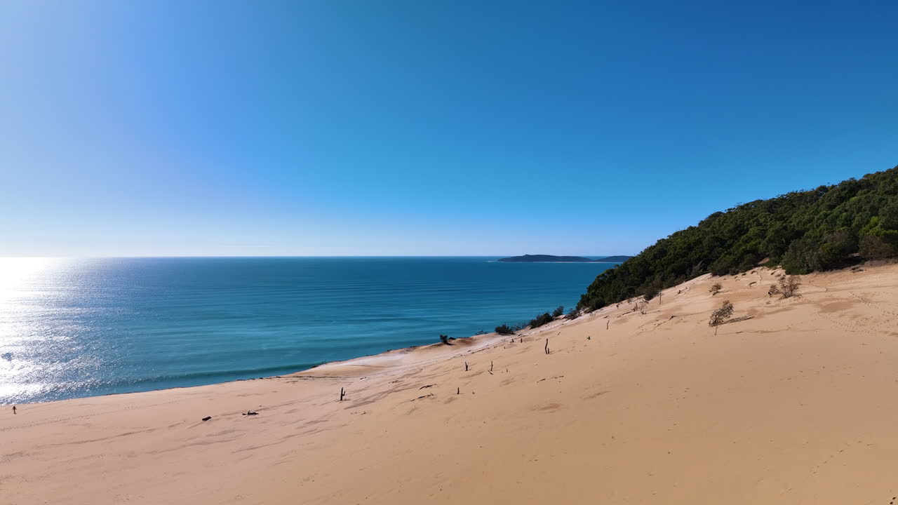 Low flight over the golden sands and scrubland of Queensland's famed Carlo Sand Blow, out towards the shimmering azure Coral Sea Rainbow Beach Australia