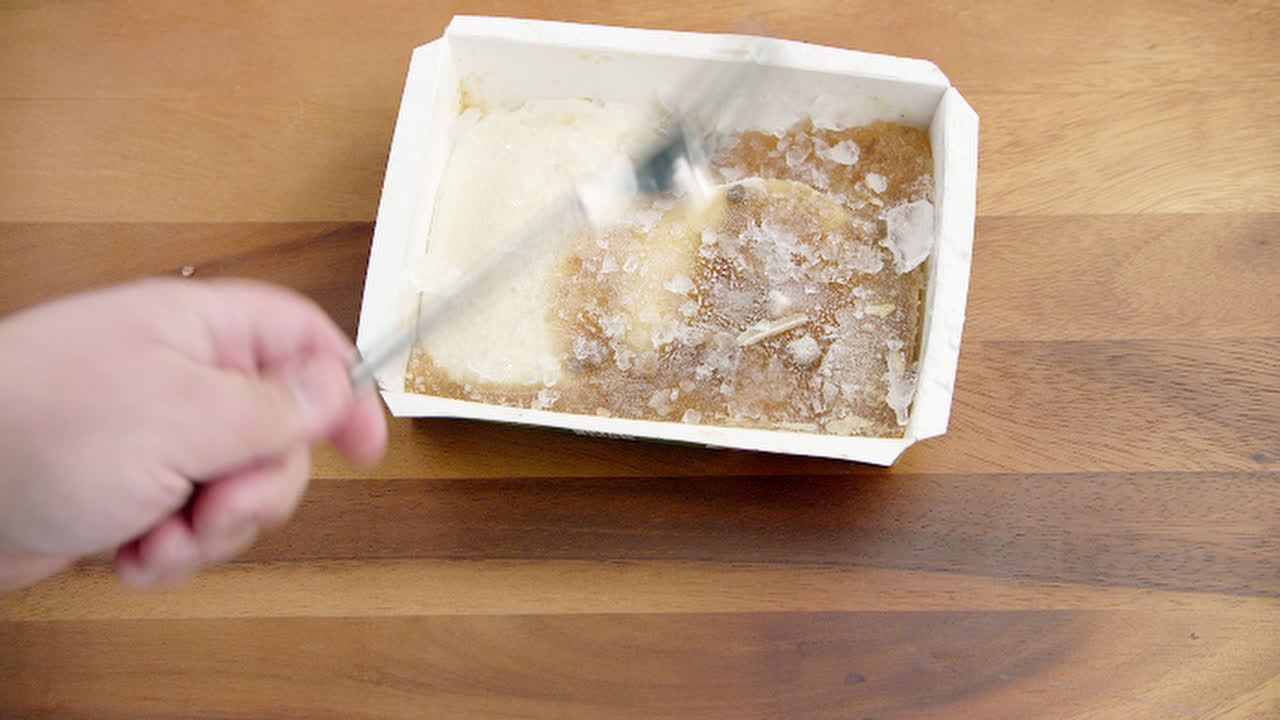 comida congelada envasada en hielo que se golpea con un tenedor de acero metálico en la mesa del comedor