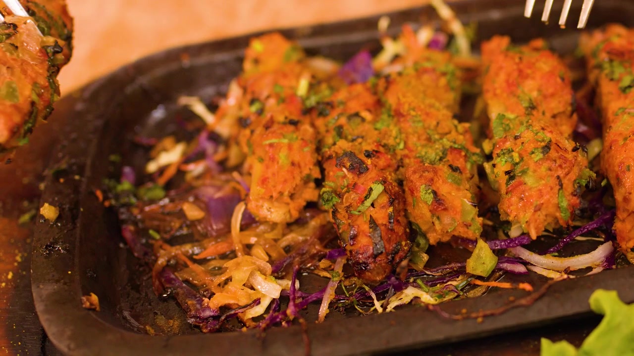 Haarukka nostaa grillattuja lihavartaita höyryävältä sizzler-lautaselta kasvisten kera.