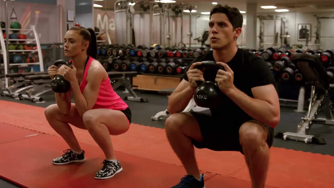 Coppia che esegue squat con pesi in palestra