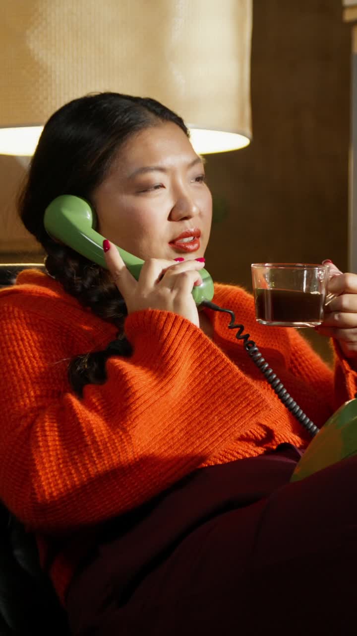 Woman having a phone call and drinking coffee at home