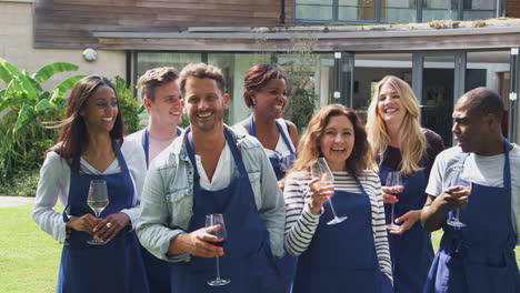 group portrait of men and women attending cookery class relaxing outdoors with glass of wine