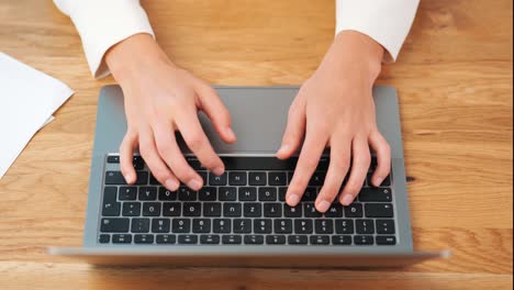 vista superior de las manos de una mujer de negocios escribiendo en el teclado del portátil