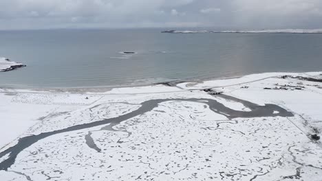 tiro con dron rodante del río gress nevado con playa gress y punto en el fondo en las hébridas exteriores de escocia
