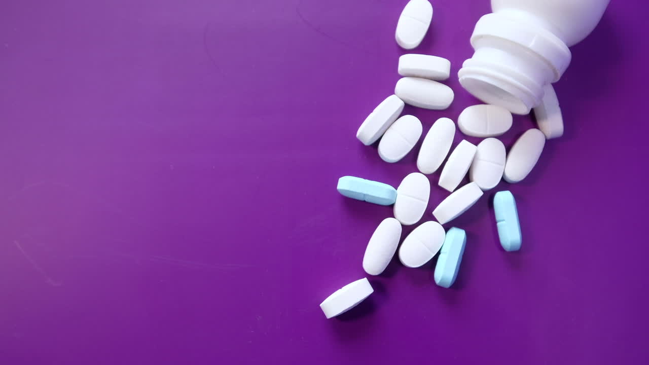 pastillas derramadas de una botella en una superficie púrpura