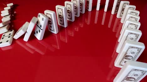 series of dominoes falling down in a row on red - chain reaction indicative of economic recession and falling stock prices in a bear market