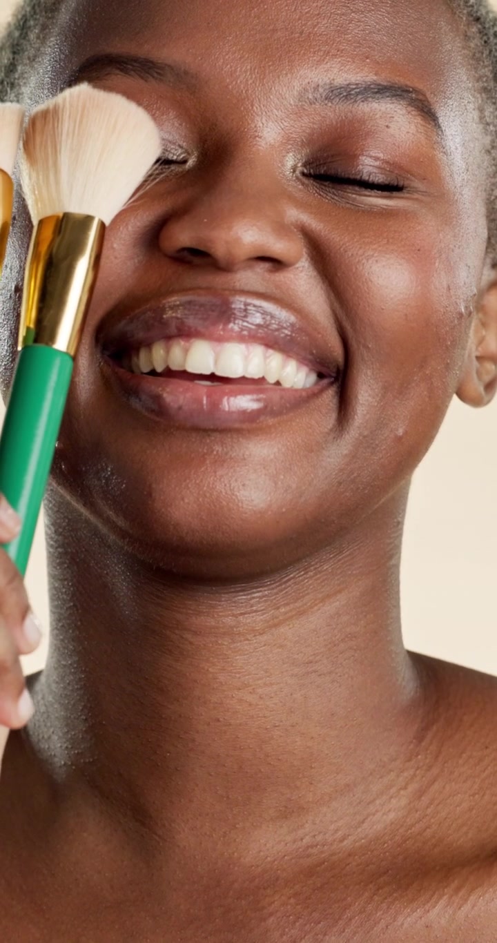 Young Woman Holding Makeup Brushes and Smiling